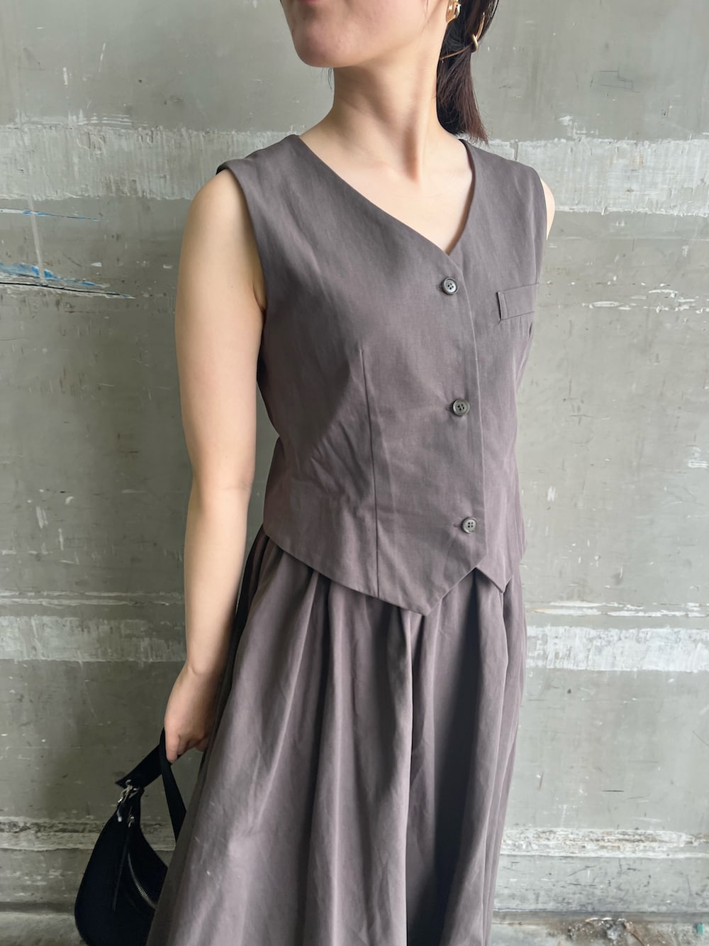 グレー系のワンピース、ブラック系のハンドバッグ、ブラック系のサンダルを着用したレディースの夏コーディネートの6枚目の写真