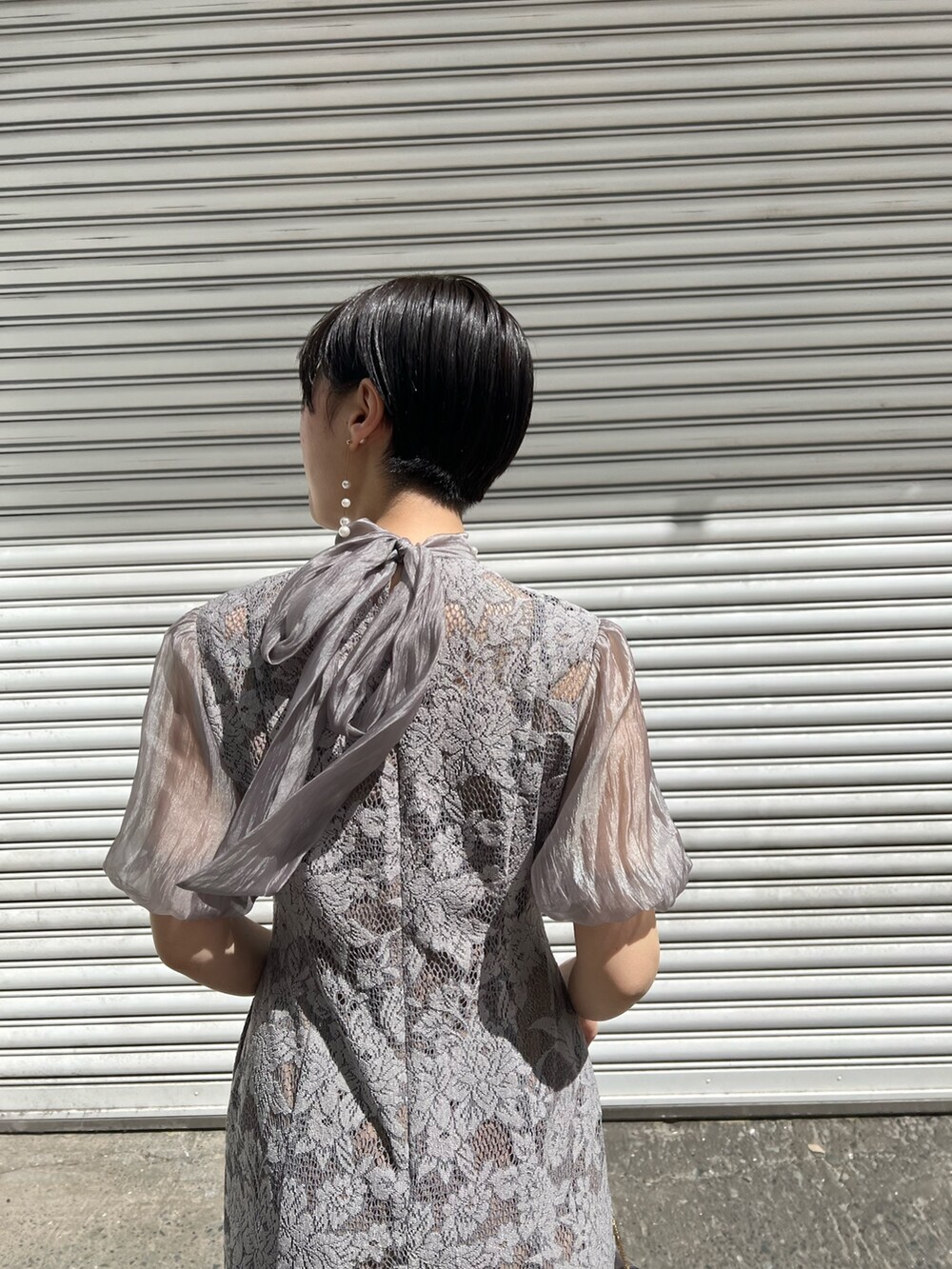 ブルー系のノーカラーコート、シルバー系のパンプス、シルバー系のクラッチバッグを着用したレディースの春コーディネートの5枚目の写真