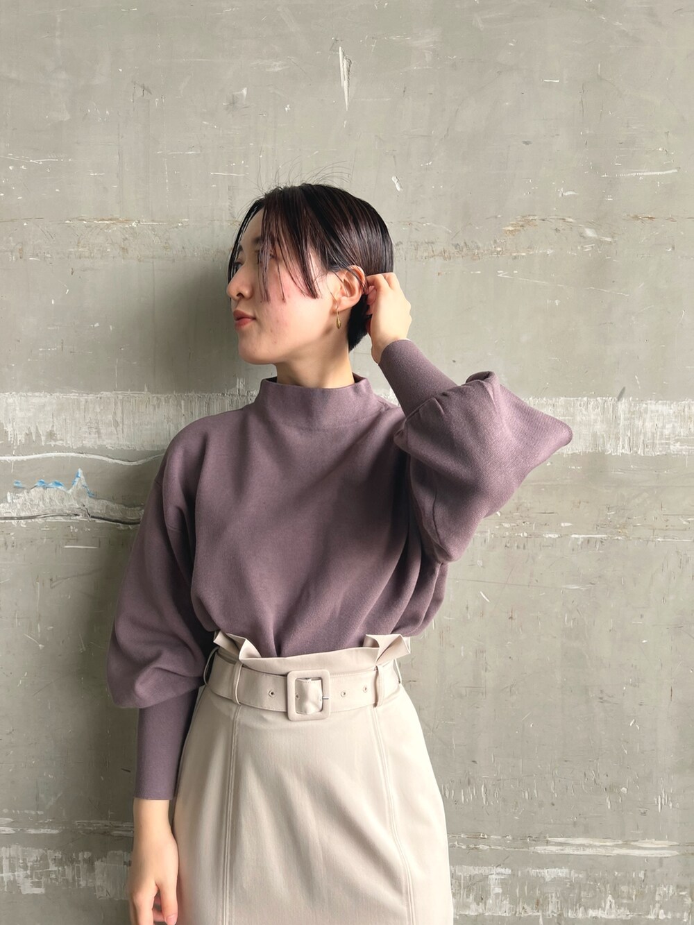 ホワイト系のノーカラーコート、ベージュ系のニット/セーター、ブラウン系のスカートを着用したレディースの秋コーディネートの7枚目の写真