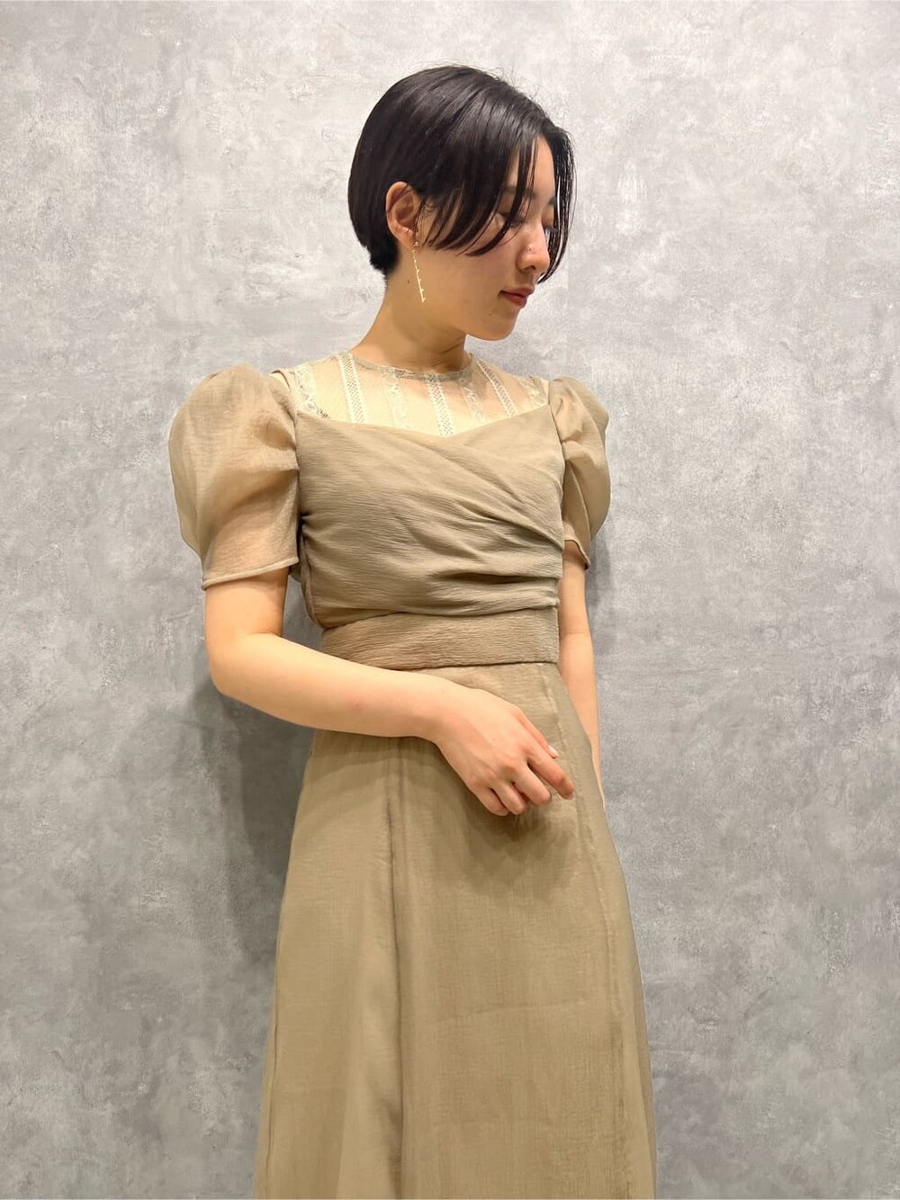 ベージュ系のドレス、ベージュ系のドレス、ゴールド系のパンプスを着用したレディースの秋コーディネートの4枚目の写真