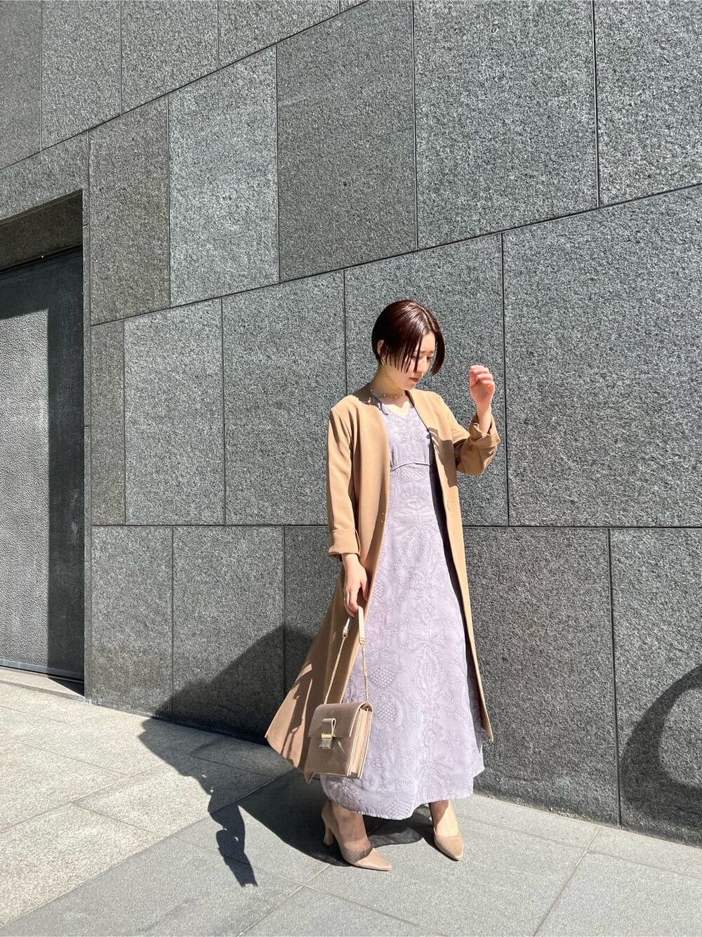 ブラウン系のクラッチバッグ、ベージュ系のその他アウター、パープル系のドレスを着用したレディースの冬コーディネートの2枚目の写真