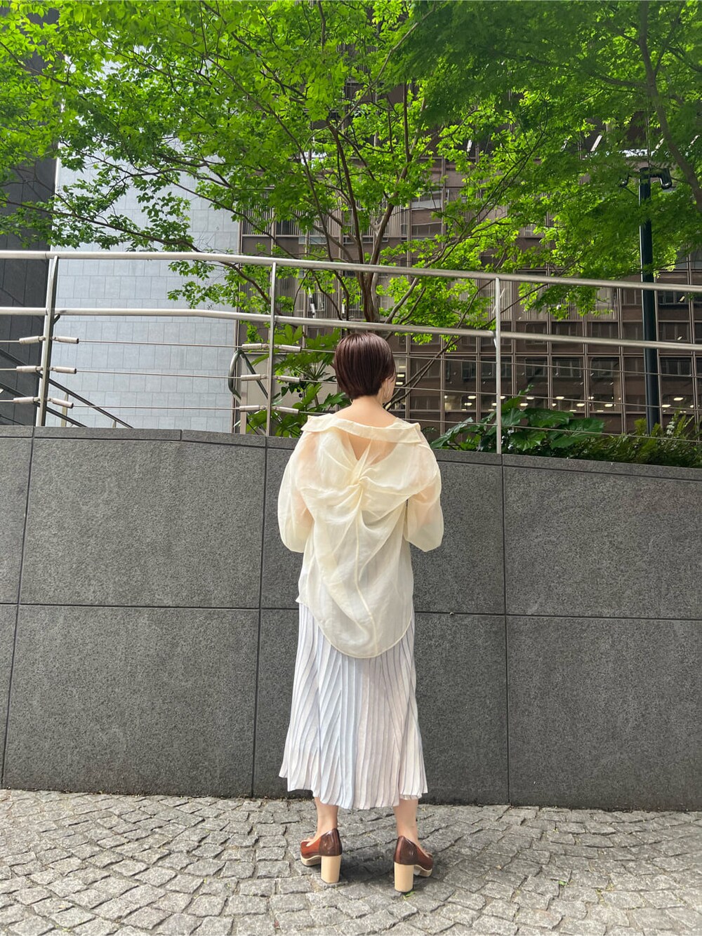 ホワイト系のシャツ/ブラウス、ブルー系のスカート、ブラウン系のパンプスを着用したレディースの春コーディネートの3枚目の写真