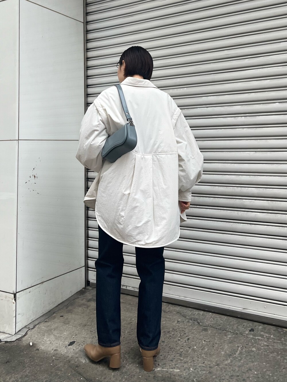 ブルー系のショルダーバッグ、ブルー系のニット/セーター、ベージュ系のブーツを着用したレディースの冬コーディネートの3枚目の写真