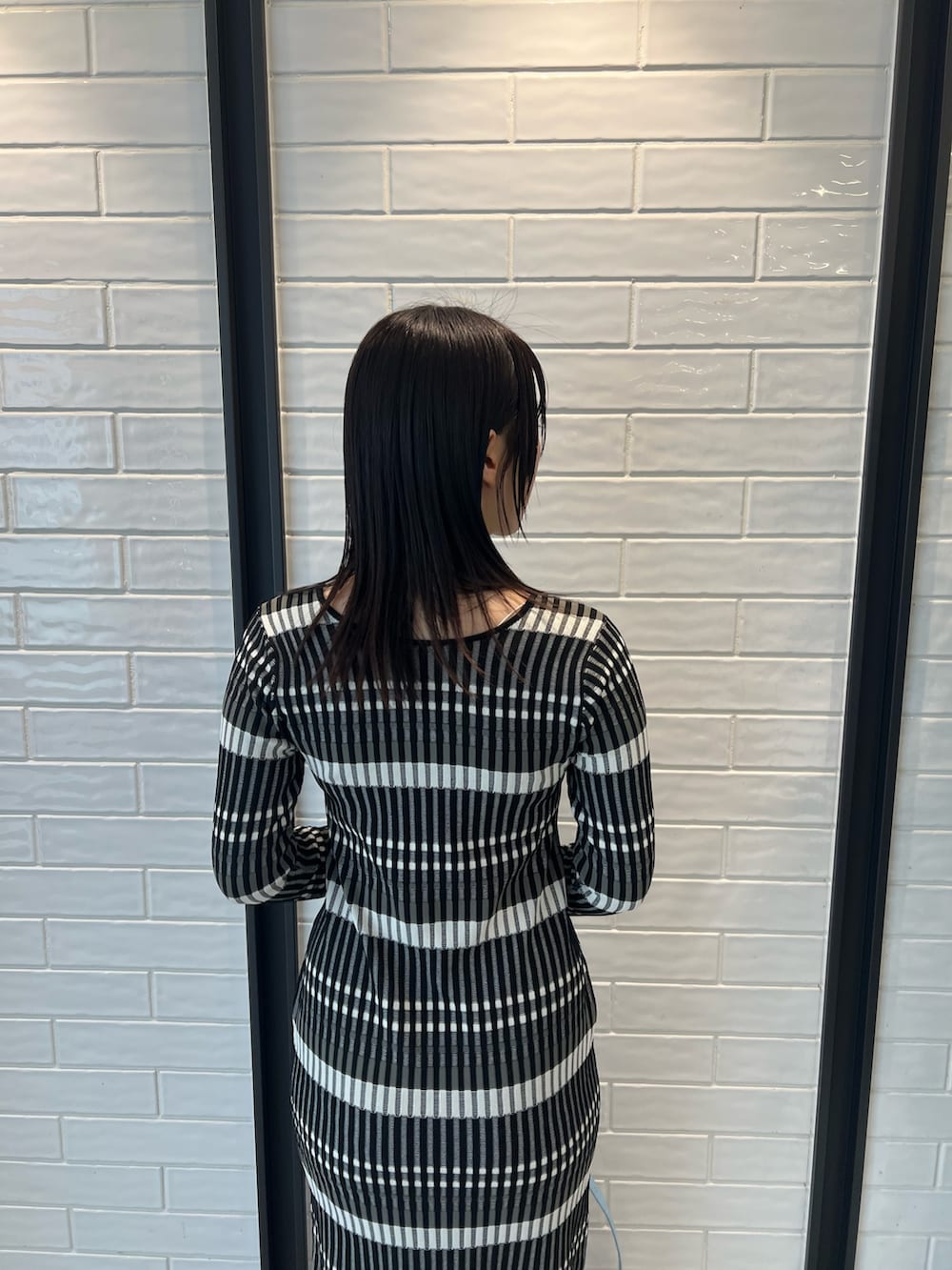 ブルー系のショルダーバッグ、ブラック系のワンピース、グレー系のスニーカーを着用したレディースの冬コーディネートの5枚目の写真