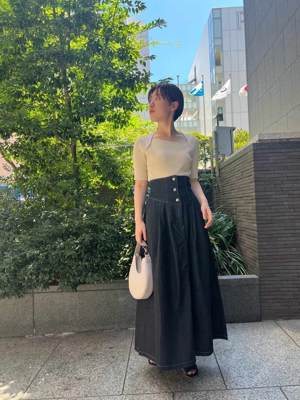 ブラック系のデニムジャケット、ブルー系のニット/セーター、ホワイト系のハンドバッグを着用したレディースの秋コーディネートの6枚目の写真