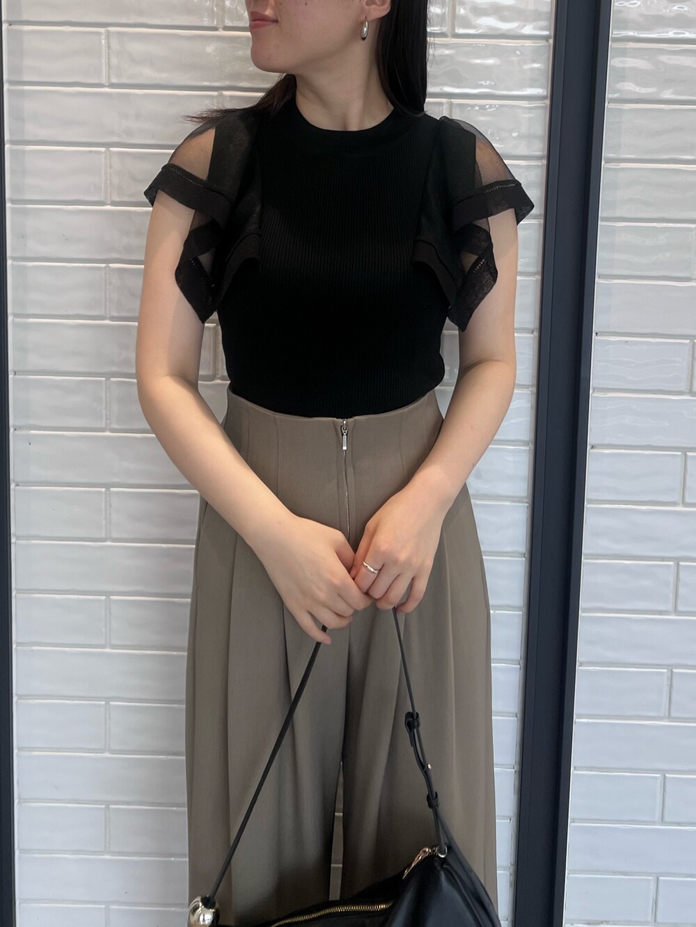 ブラウン系のその他パンツ、ブラック系のニット/セーター、ブラック系のサンダルを着用したレディースの春コーディネートの4枚目の写真