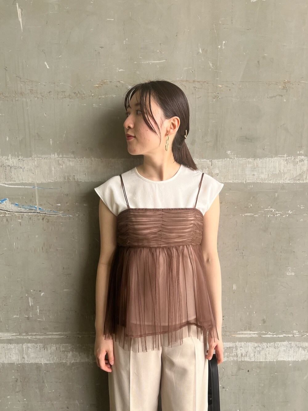 ブラック系のサンダル、ブラック系のショルダーバッグ、ホワイト系のスラックスを着用したレディースの夏コーディネートの3枚目の写真