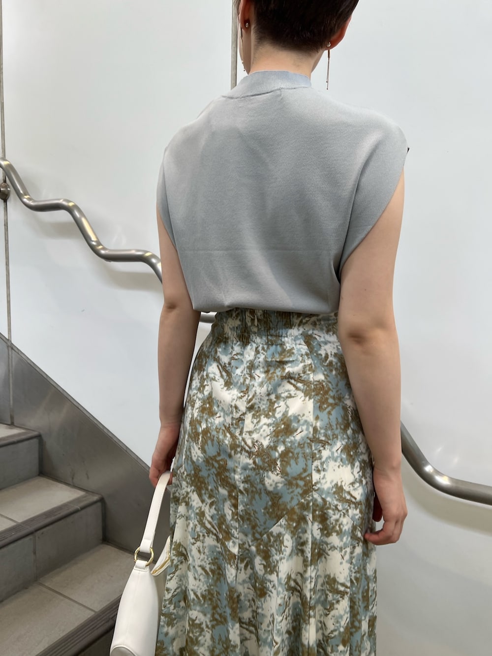 ベージュ系のサンダル、ホワイト系のハンドバッグ、グリーン系のスカートを着用したレディースの夏コーディネートの4枚目の写真