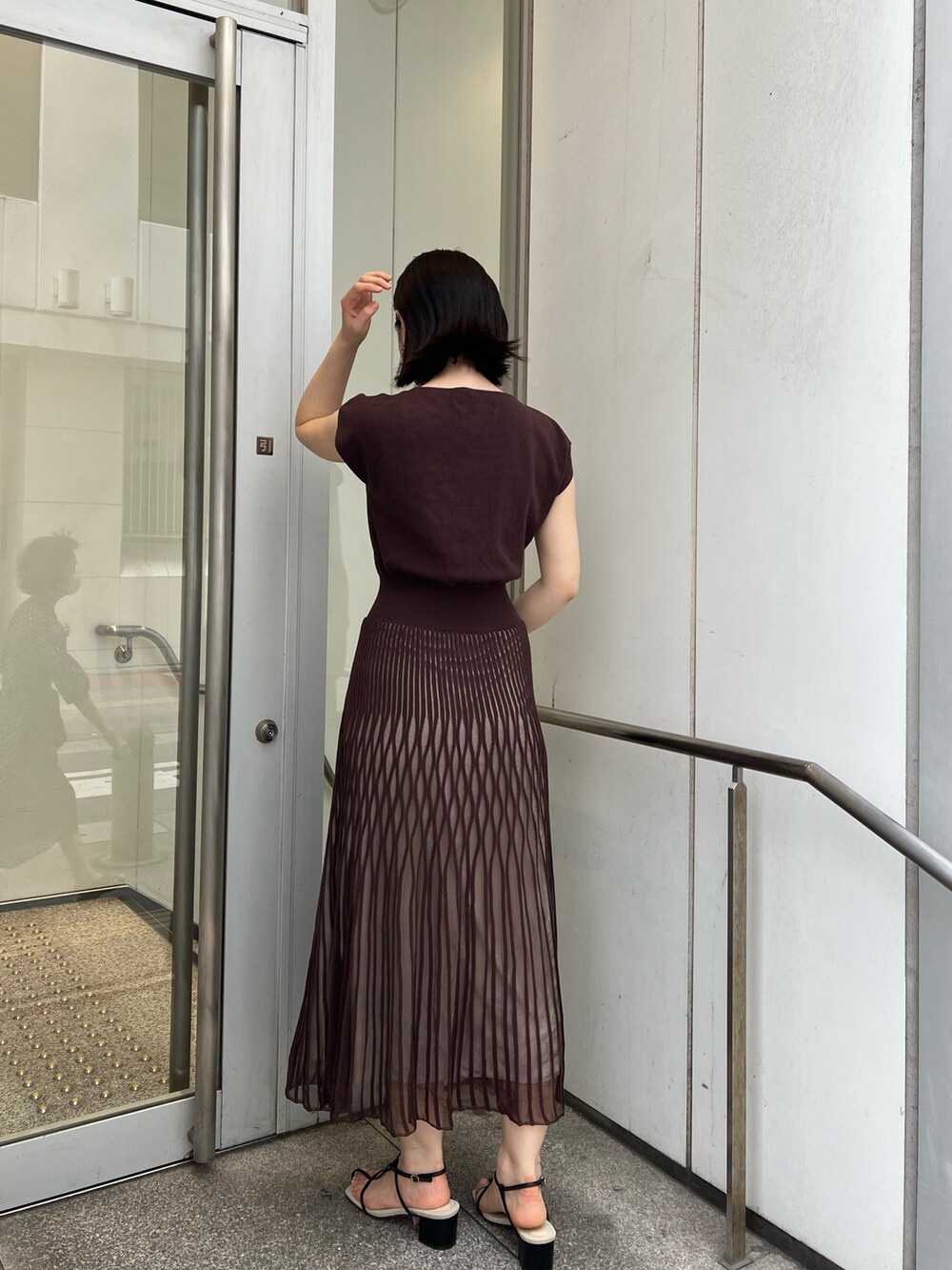 ブラック系のサンダル、ブラック系のハンドバッグ、ブラウン系のワンピースを着用したレディースの夏コーディネートの3枚目の写真