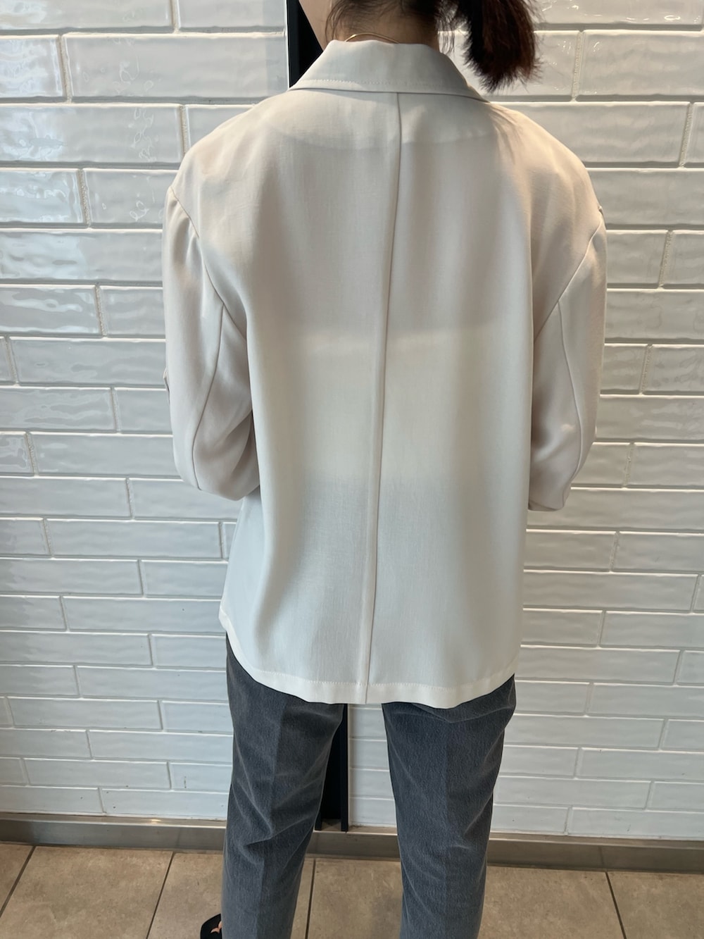 ホワイト系のキャミソール、ブラック系のデニムパンツ、ベージュ系のテーラードジャケットを着用したレディースの夏コーディネートの4枚目の写真