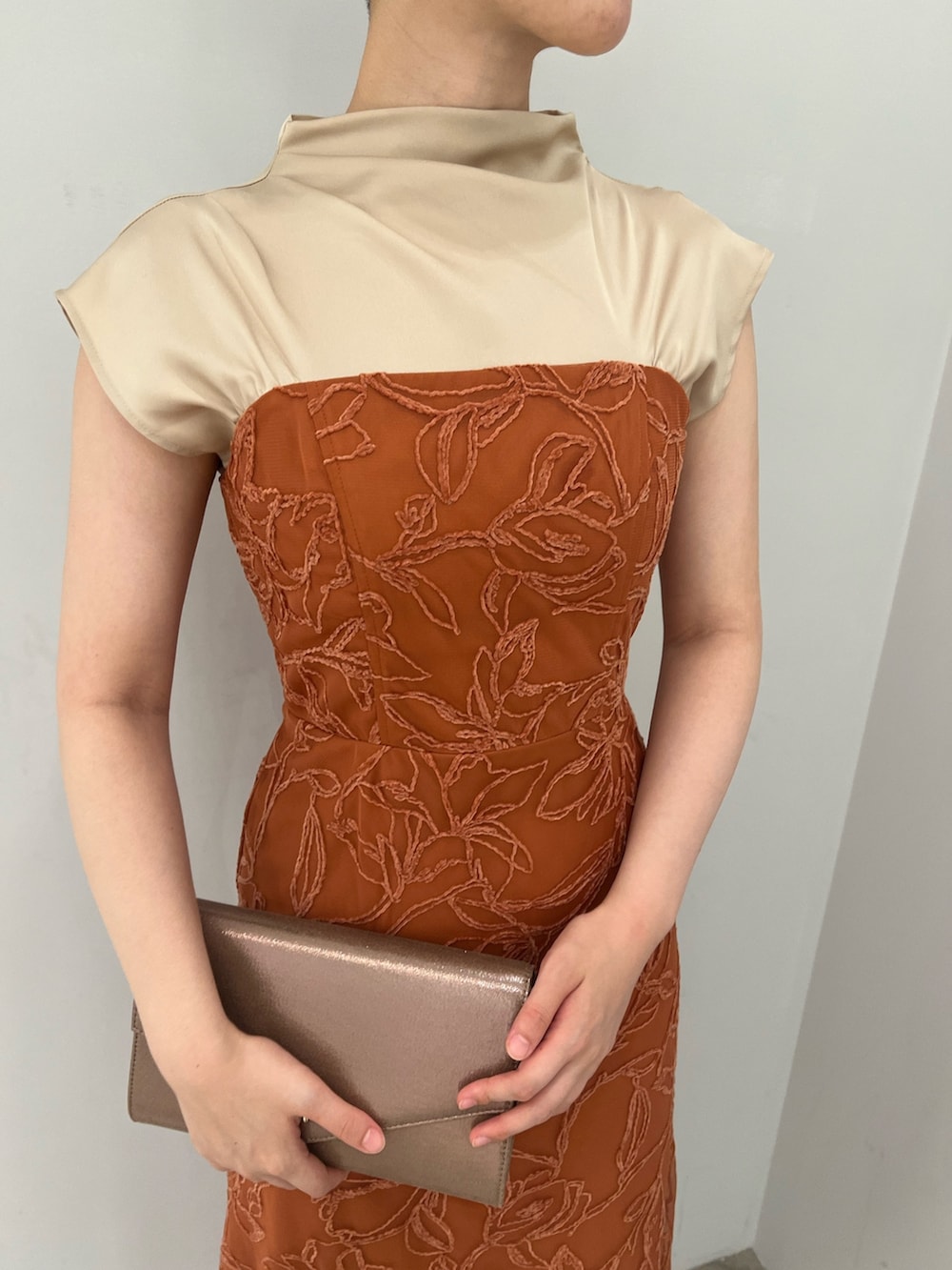 ゴールド系のパンプス、ゴールド系のハンドバッグ、オレンジ系のドレスを着用したレディースの夏コーディネートの3枚目の写真