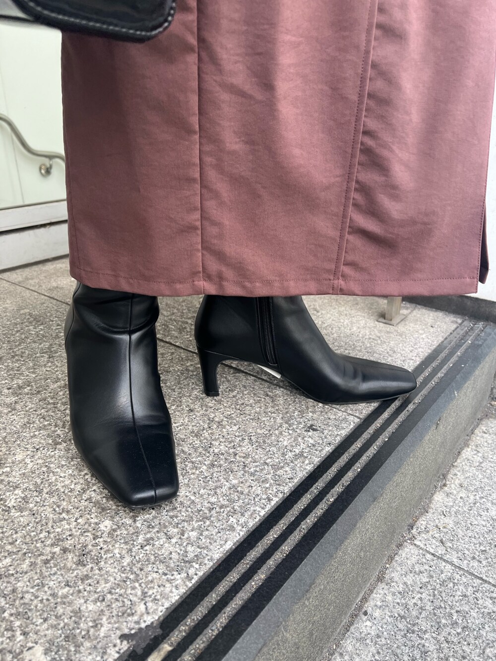 ブラック系のショルダーバッグ、ブラウン系のワンピース、ブラック系のブーツを着用したレディースの秋コーディネートの9枚目の写真