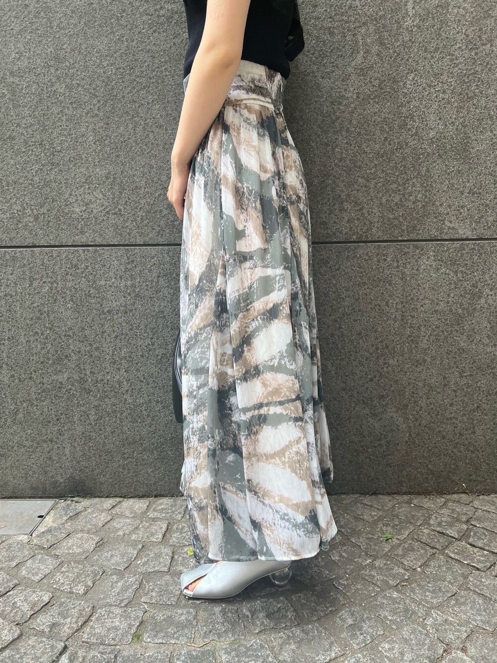 ブラック系のニット/セーター、グレー系のスカート、ブラック系のショルダーバッグを着用したレディースの春コーディネートの8枚目の写真