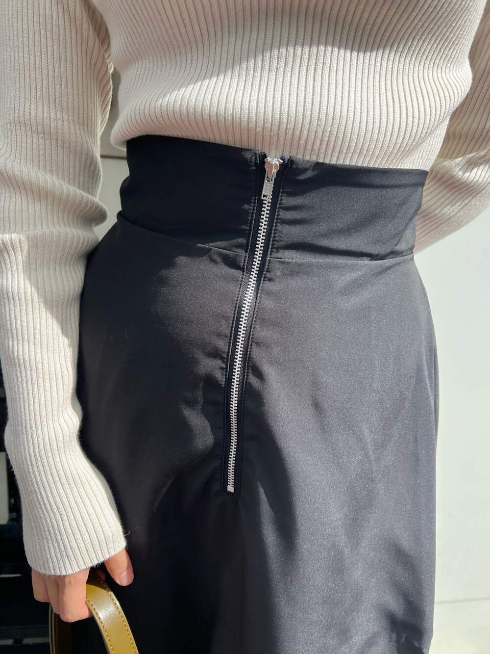 ホワイト系のニット/セーター、ブラック系のブーツ、ブラック系のスカートを着用したレディースの秋コーディネートの6枚目の写真