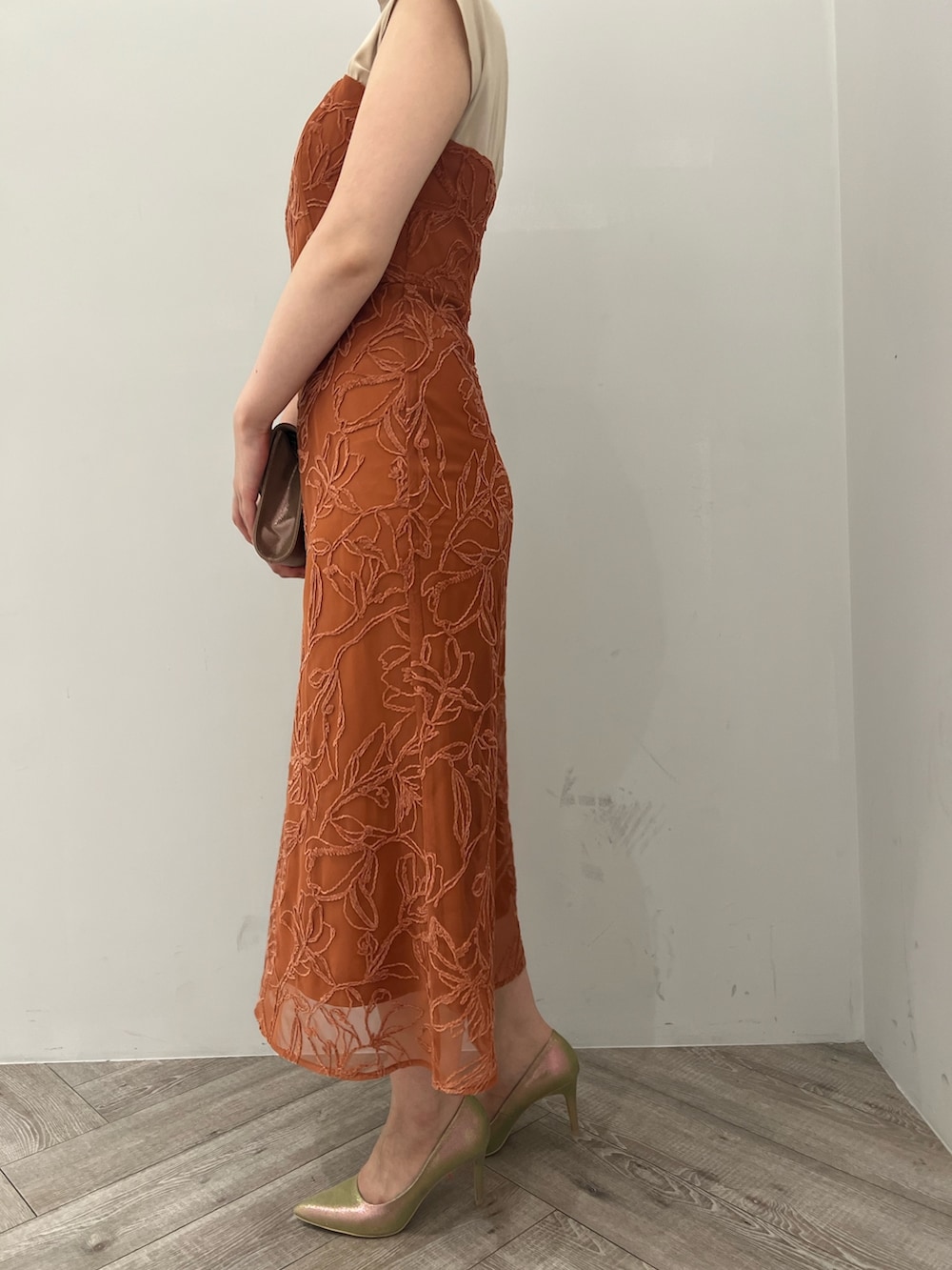 ゴールド系のパンプス、ゴールド系のハンドバッグ、オレンジ系のドレスを着用したレディースの夏コーディネートの7枚目の写真