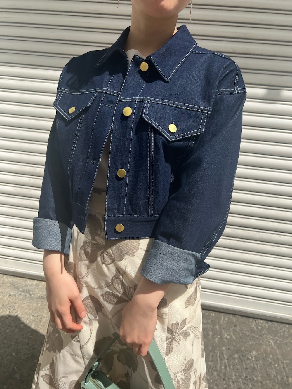 グリーン系のハンドバッグ、ホワイト系のニット/セーター、ベージュ系のサンダルを着用したレディースの春コーディネートの4枚目の写真