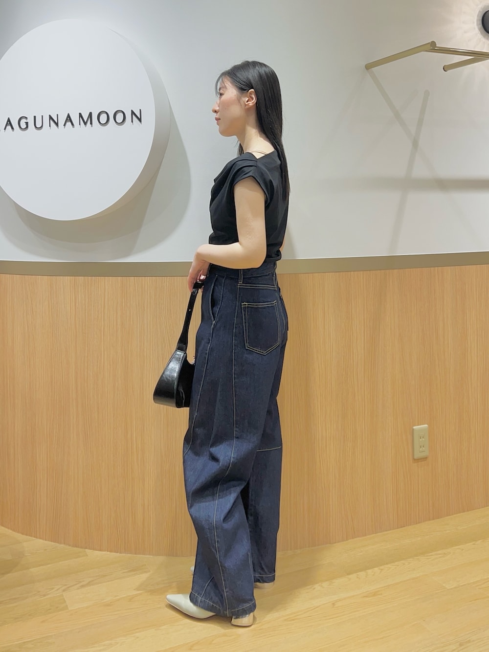 ブルー系のデニムパンツ、グリーン系のパンプス、ブラック系のTシャツ/カットソーを着用したレディースの春コーディネートの2枚目の写真