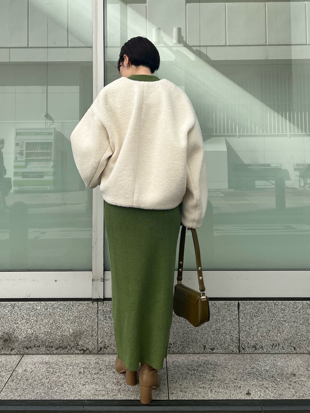 ブラウン系のショルダーバッグ、ベージュ系のブーツ、グリーン系のワンピースを着用したレディースの秋コーディネートの2枚目の写真