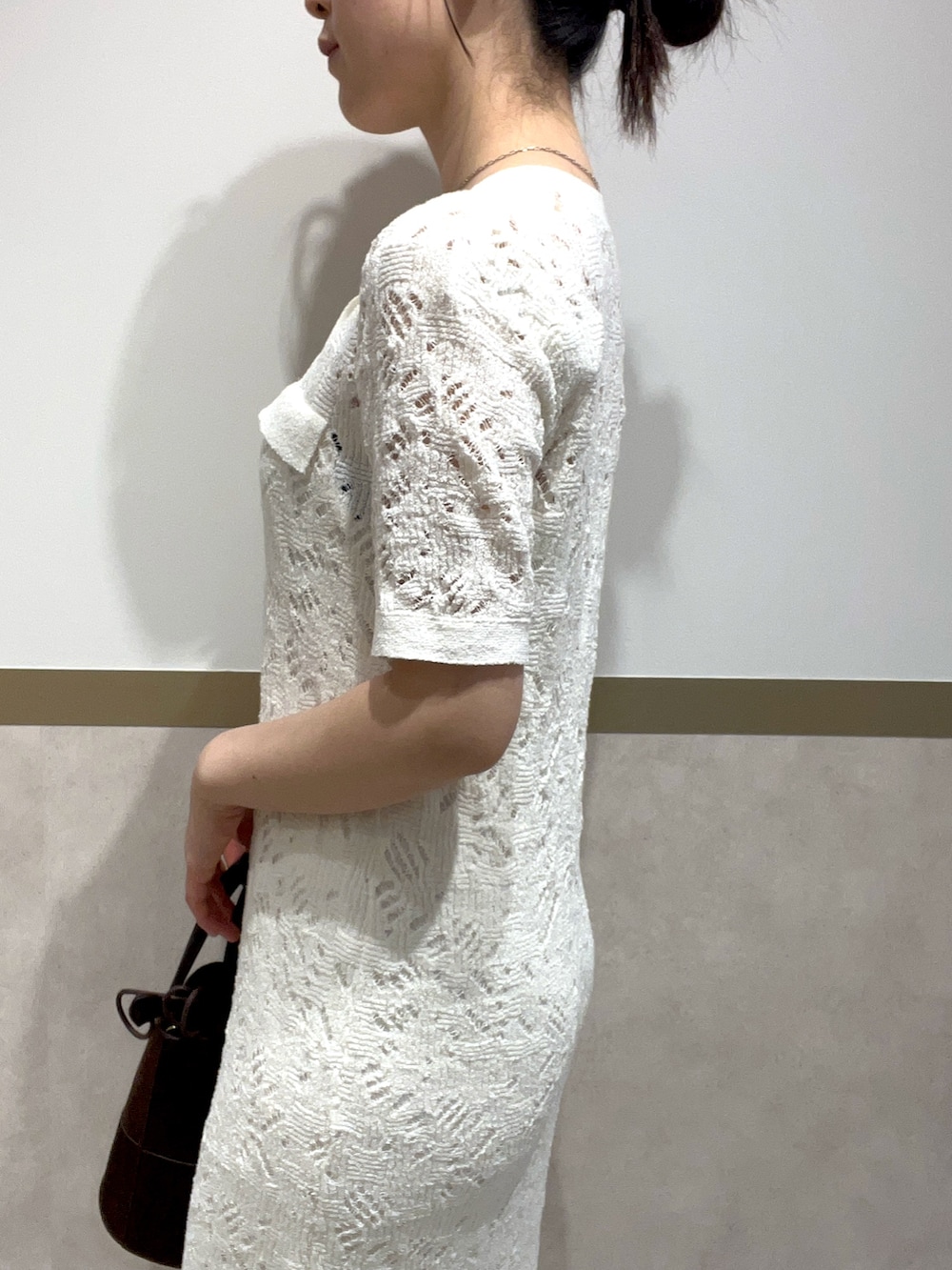 ホワイト系のワンピース、グリーン系のパンプス、ブラウン系のハンドバッグを着用したレディースの春コーディネートの5枚目の写真