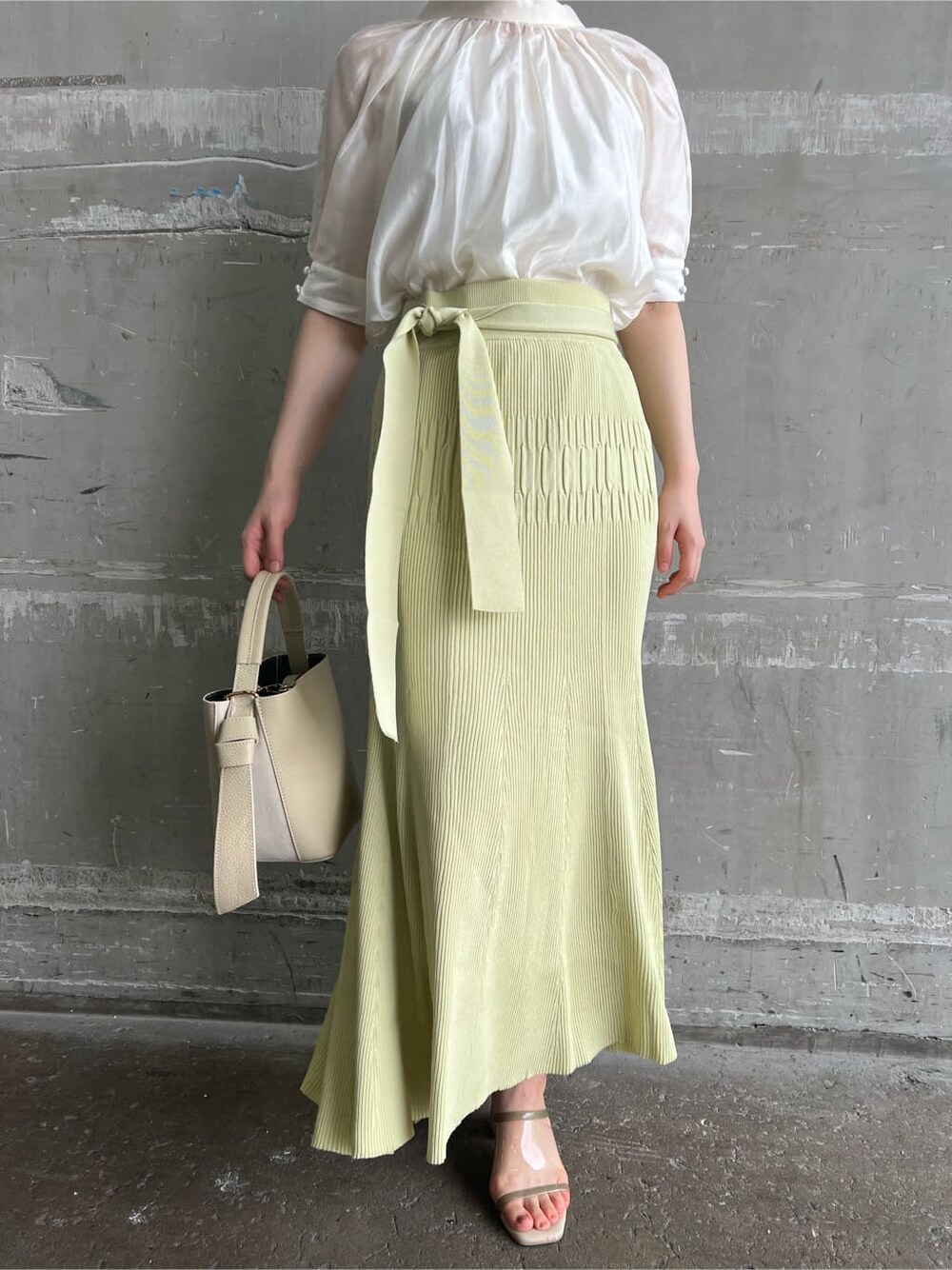 ホワイト系のハンドバッグ、グリーン系のサンダル、イエロー系のスカートを着用したレディースの夏コーディネートの7枚目の写真