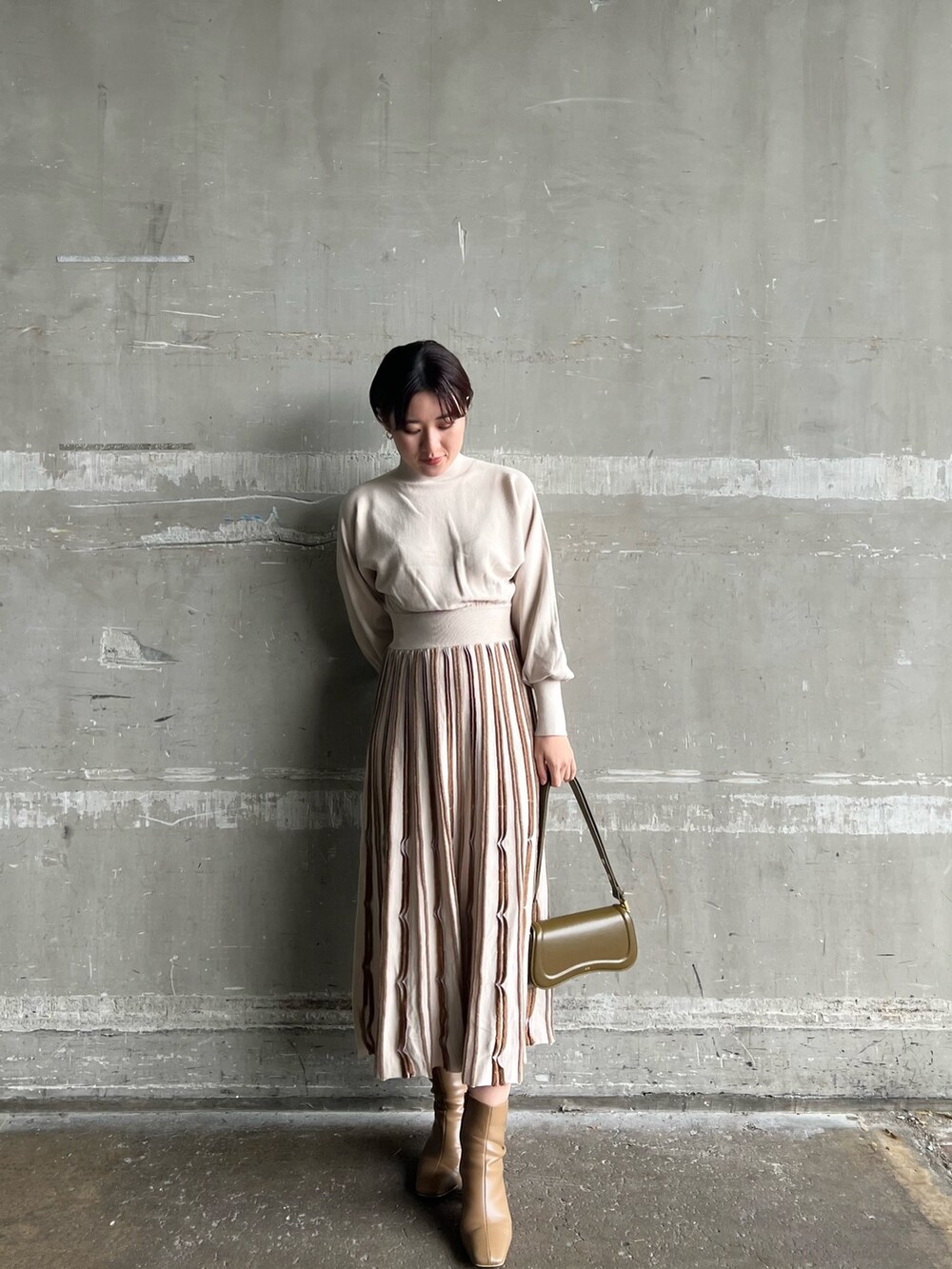 ブラウン系のショルダーバッグ、ベージュ系のブーツ、グレー系のその他アウターを着用したレディースの冬コーディネートの7枚目の写真