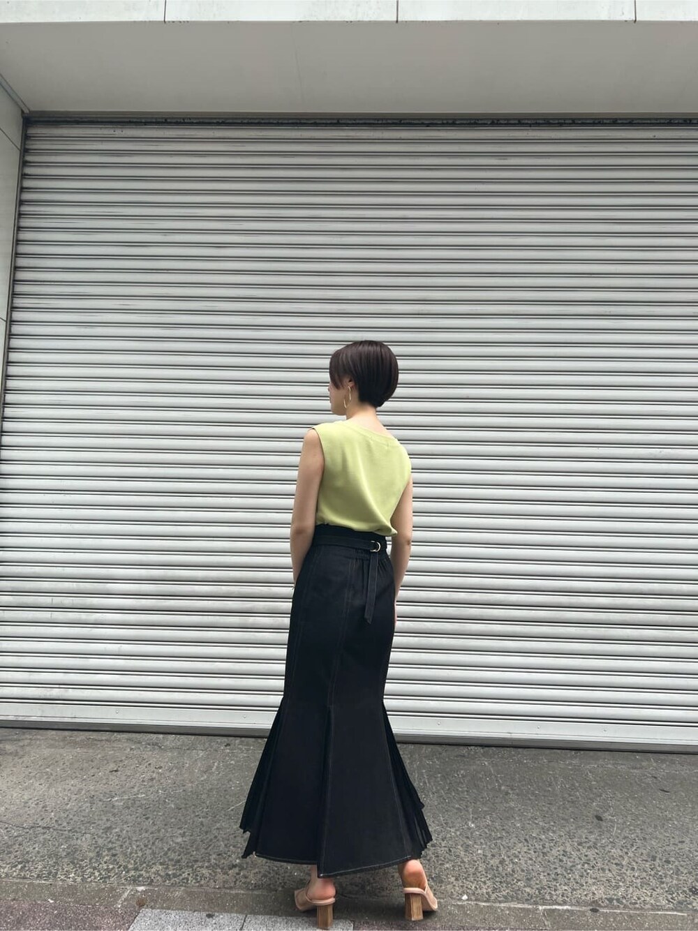 ブルー系のスカート、ベージュ系のサンダル、イエロー系のニット/セーターを着用したレディースの春コーディネートの3枚目の写真