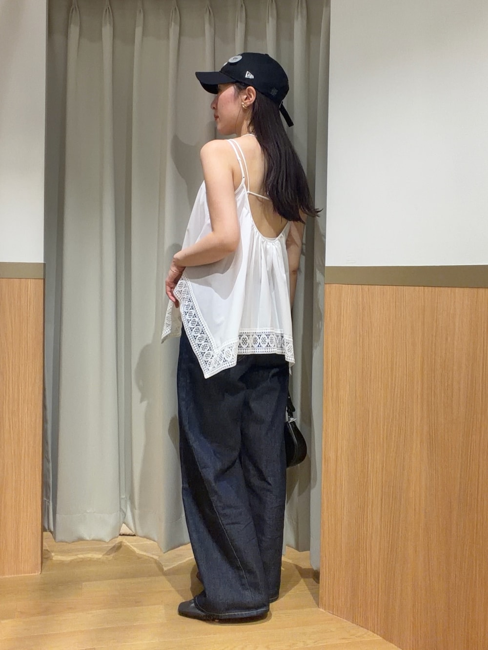 ブルー系のデニムパンツ、ホワイト系のキャミソール、ブラウン系のサンダルを着用したレディースの夏コーディネートの2枚目の写真