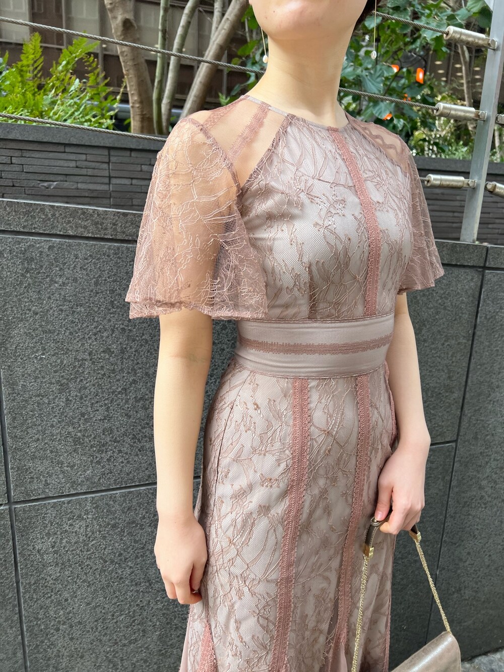 ゴールド系のハンドバッグ、ゴールド系のパンプス、ベージュ系のノーカラーコートを着用したレディースの冬コーディネートの9枚目の写真