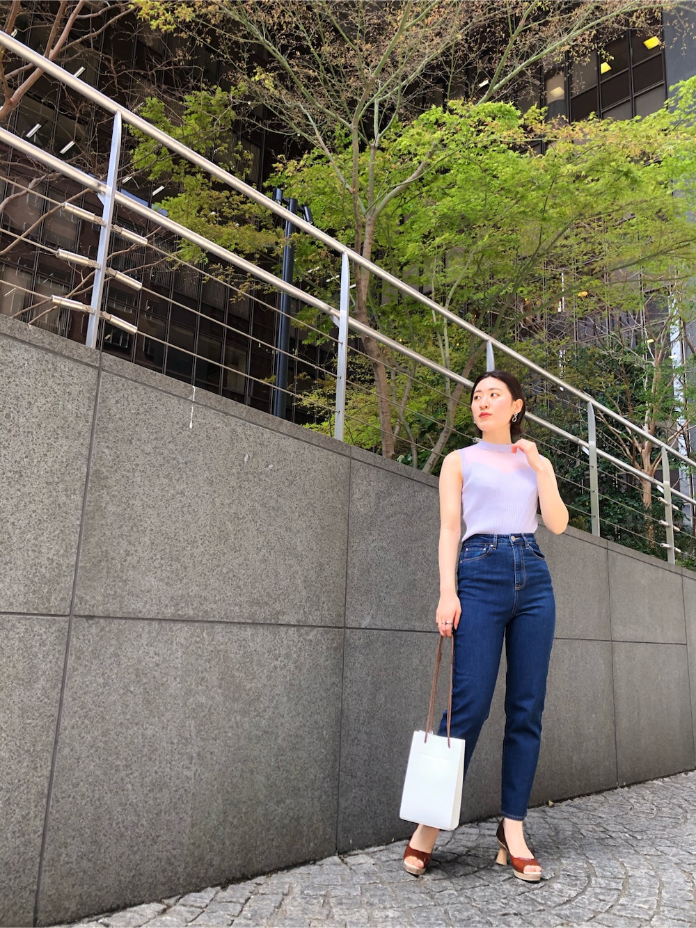 ブラウン系のパンプス、ブルー系のデニムパンツ、ホワイト系のハンドバッグを着用したレディースの春コーディネートの2枚目の写真