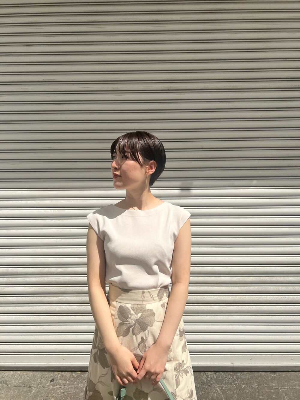 グリーン系のハンドバッグ、ホワイト系のニット/セーター、ベージュ系のサンダルを着用したレディースの春コーディネートの9枚目の写真