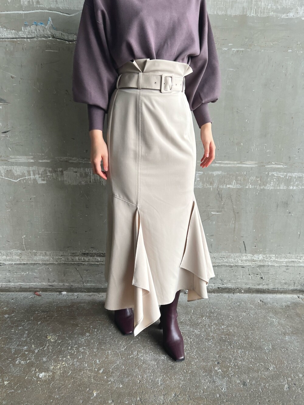 ホワイト系のノーカラーコート、ベージュ系のニット/セーター、ブラウン系のスカートを着用したレディースの秋コーディネートの9枚目の写真