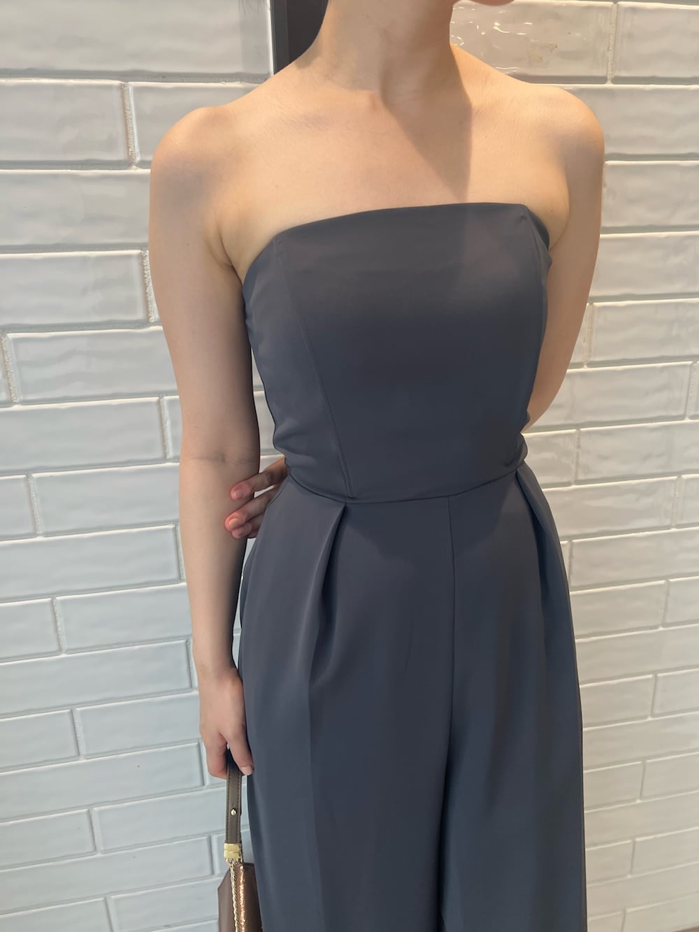 ゴールド系のハンドバッグ、ゴールド系のパンプス、グレー系のパンツドレスを着用したレディースの夏コーディネートの10枚目の写真