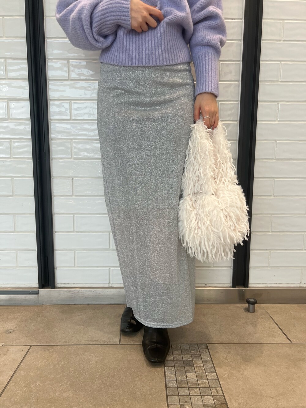 パープル系のニット/セーター、シルバー系のスカートを着用したレディースの冬コーディネートの6枚目の写真