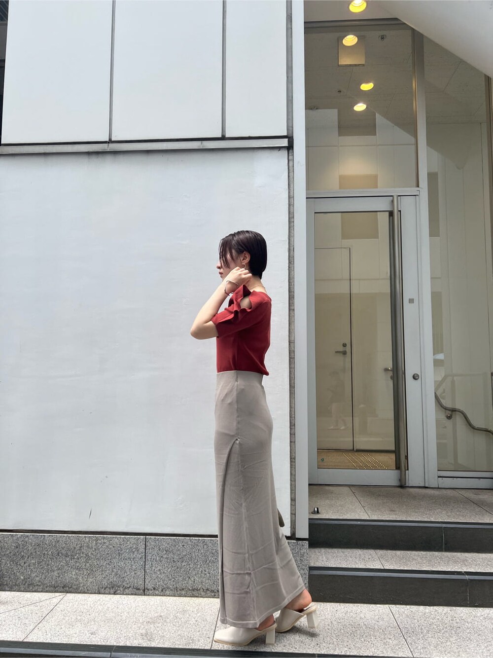 ベージュ系のハンドバッグ、ホワイト系のサンダル、ベージュ系のスカートを着用したレディースの夏コーディネートの2枚目の写真