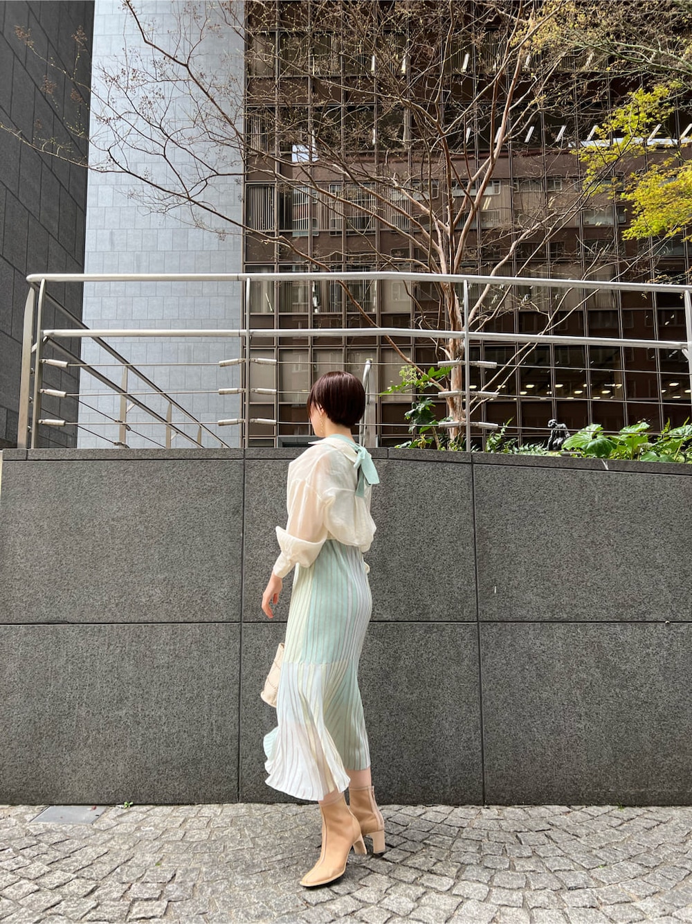 ホワイト系のショルダーバッグ、ベージュ系のブーツ、グリーン系のワンピースを着用したレディースの春コーディネートの3枚目の写真