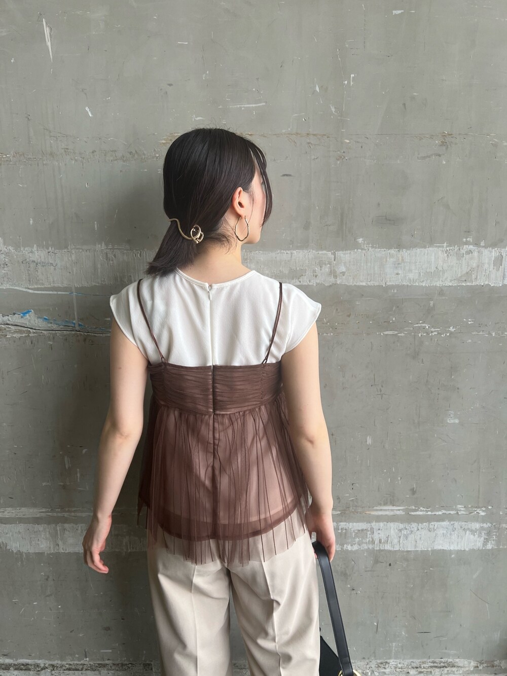 ブラック系のサンダル、ブラック系のショルダーバッグ、ホワイト系のスラックスを着用したレディースの夏コーディネートの4枚目の写真