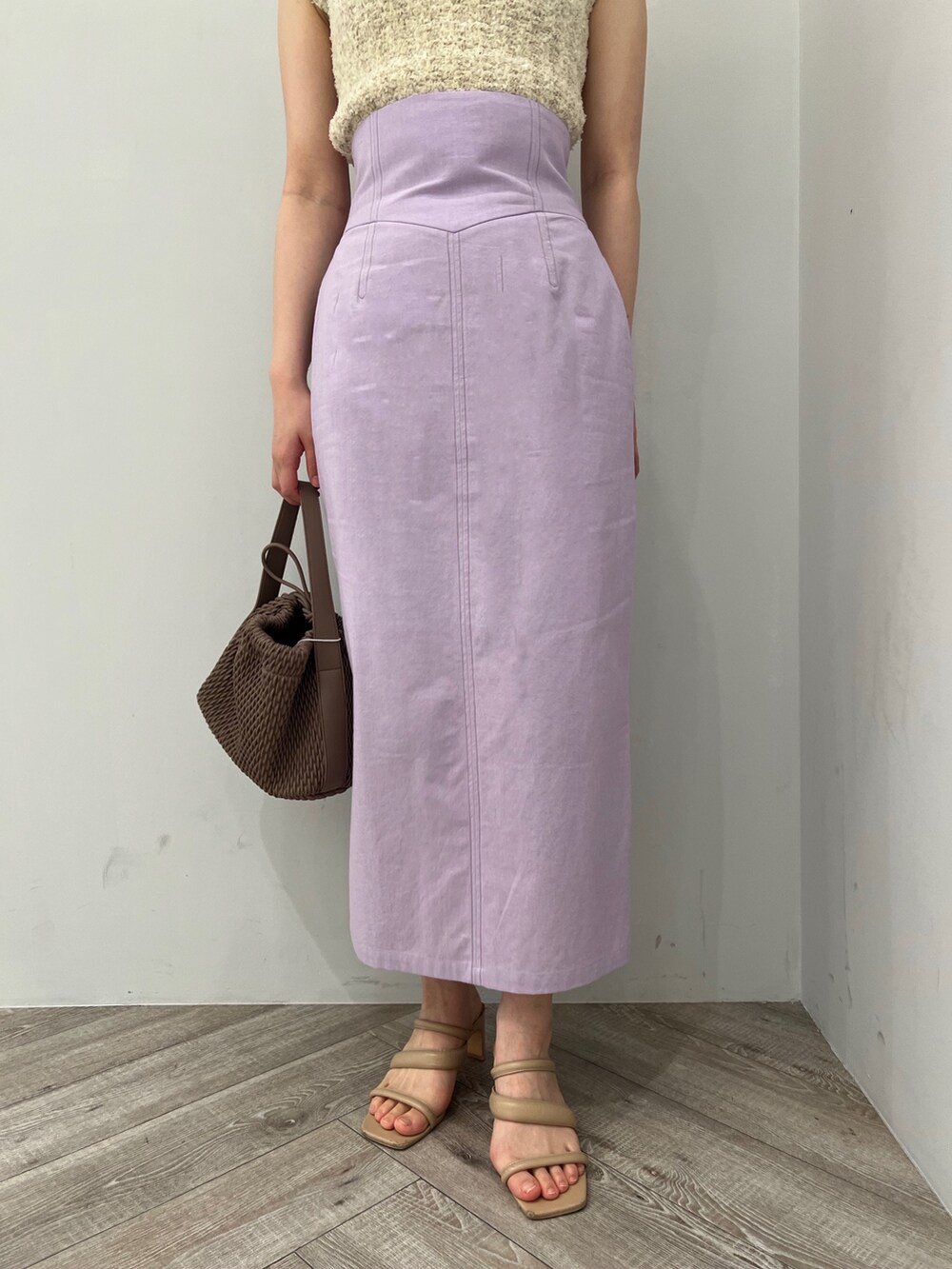 ホワイト系のハンドバッグ、ホワイト系のニット/セーター、パープル系のスカートを着用したレディースの春コーディネートの2枚目の写真