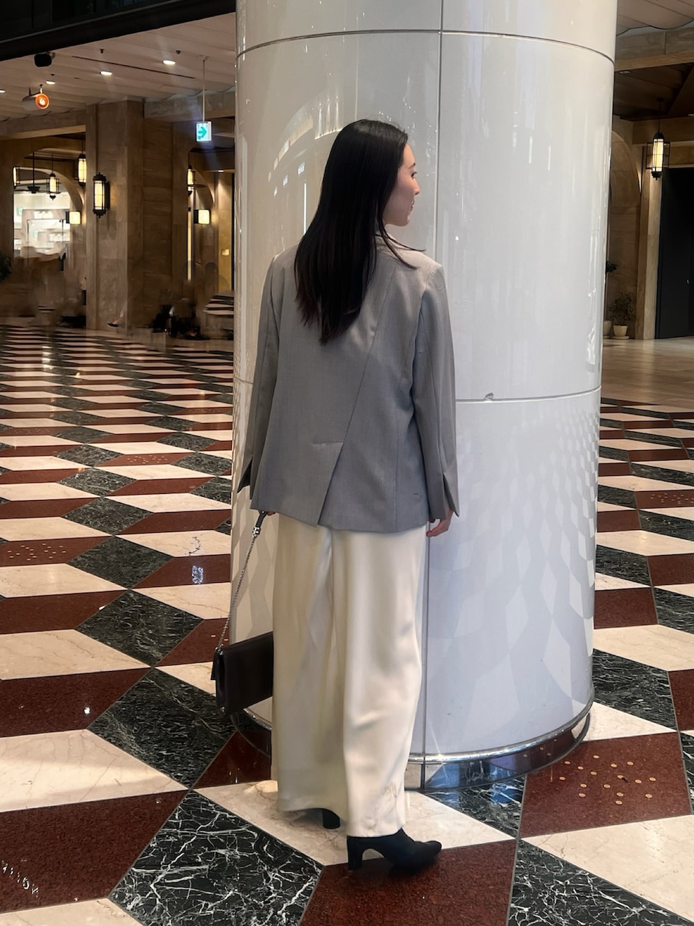 グレー系のテーラードジャケット、イエロー系のドレス、シルバー系のクラッチバッグを着用したレディースの冬コーディネートの3枚目の写真