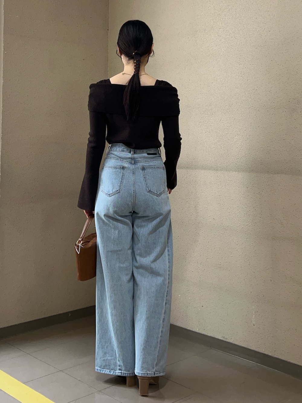 ブルー系のデニムパンツ、ブラウン系のニット/セーター、イエロー系のハンドバッグを着用したレディースの冬コーディネートの3枚目の写真