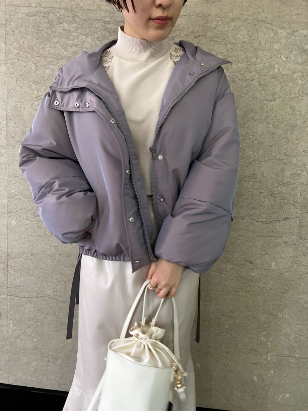 グレー系のスカート、パープル系のその他アウター、ホワイト系のハンドバッグを着用したレディースの冬コーディネートの4枚目の写真