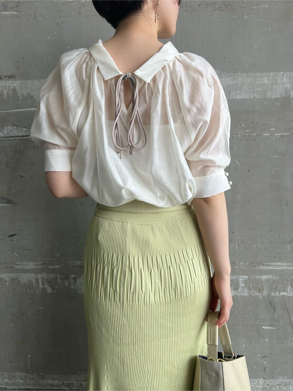 ホワイト系のハンドバッグ、グリーン系のサンダル、イエロー系のスカートを着用したレディースの夏コーディネートの5枚目の写真