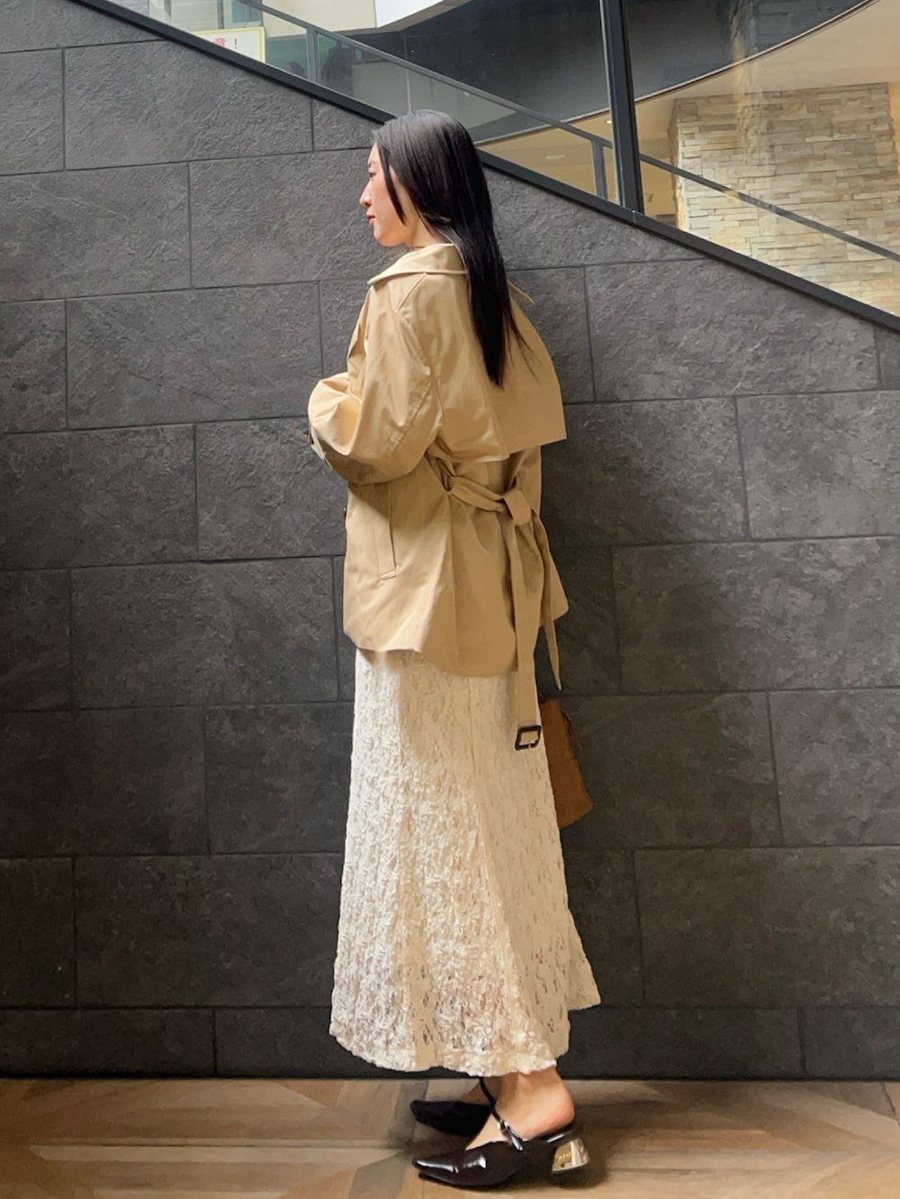 ブラウン系のハンドバッグ、ホワイト系のワンピース、ベージュ系のトレンチコートを着用したレディースの冬コーディネートの2枚目の写真