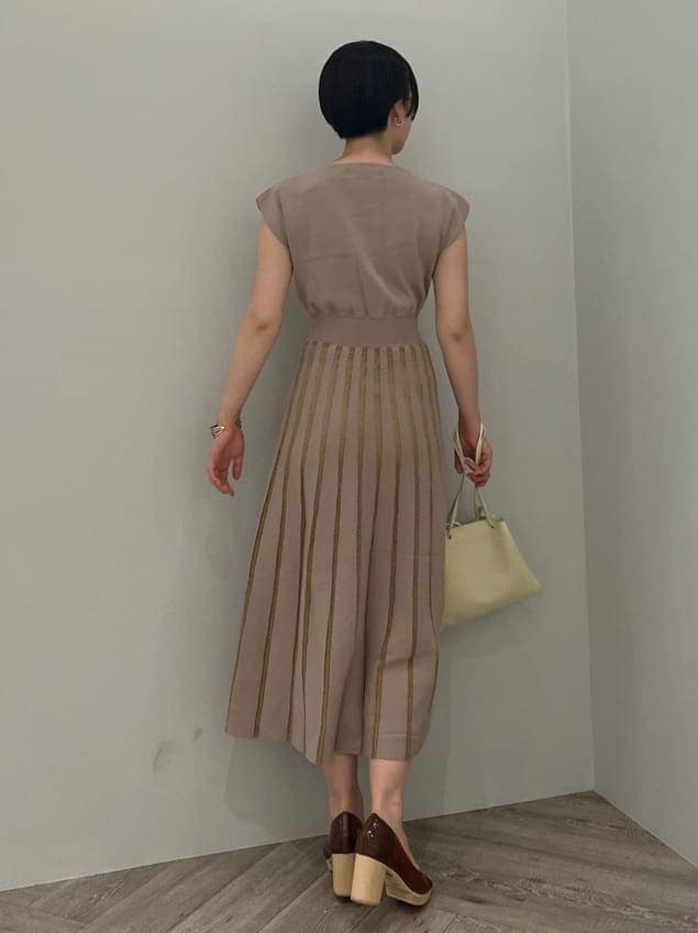 ホワイト系のハンドバッグ、ブラウン系のパンプス、ベージュ系のワンピースを着用したレディースの夏コーディネートの3枚目の写真