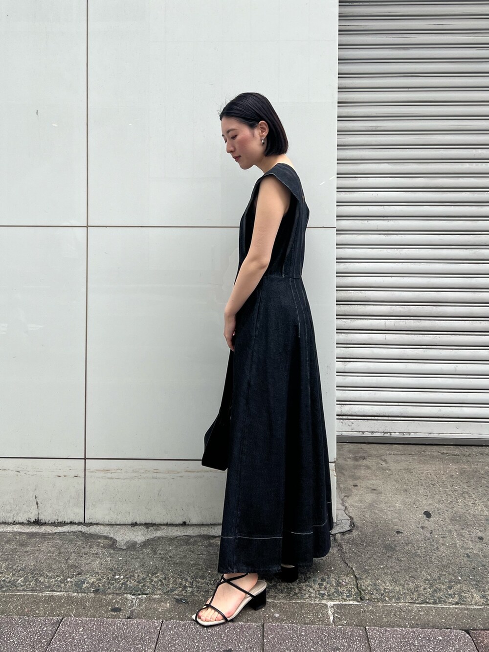 ブラック系のワンピース、ブラック系のサンダル、ブラック系のハンドバッグを着用したレディースの春コーディネートの5枚目の写真