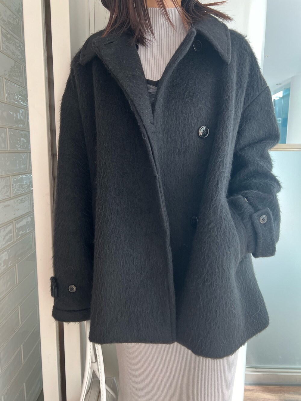 ブラック系のステンカラーコート、ブルー系のワンピース、ブラック系のブーツを着用したレディースの冬コーディネートの5枚目の写真