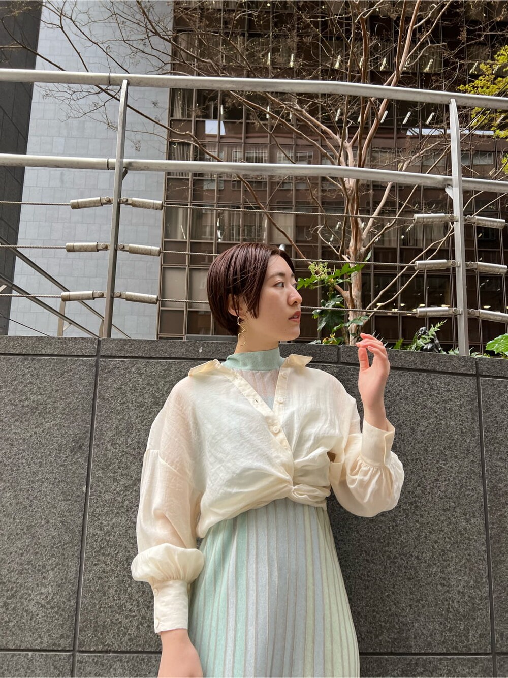 ホワイト系のショルダーバッグ、ベージュ系のブーツ、グリーン系のワンピースを着用したレディースの春コーディネートの4枚目の写真