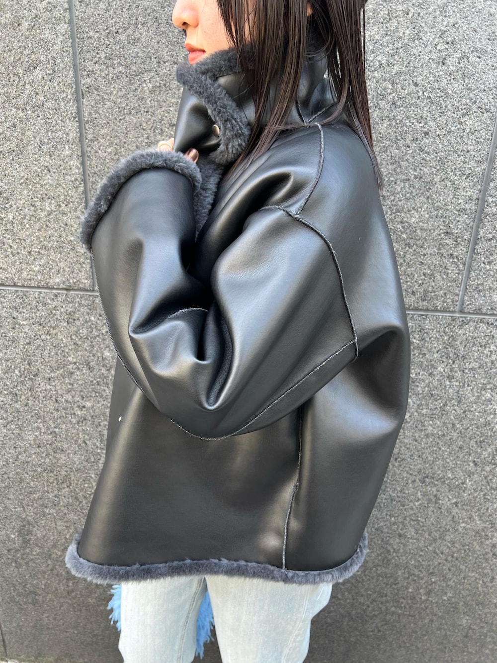 グレー系のムートンコート、ブルー系のデニムパンツを着用したレディースの冬コーディネートの7枚目の写真