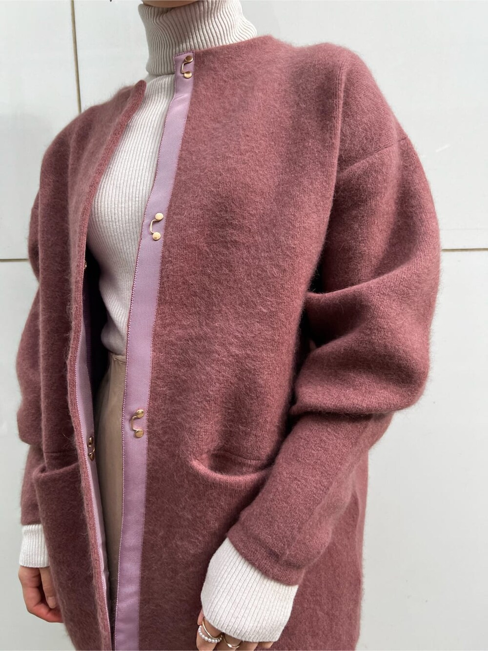 ベージュ系のスカート、ホワイト系のその他シューズ、ピンク系のカーディガン/ボレロを着用したレディースの冬コーディネートの3枚目の写真