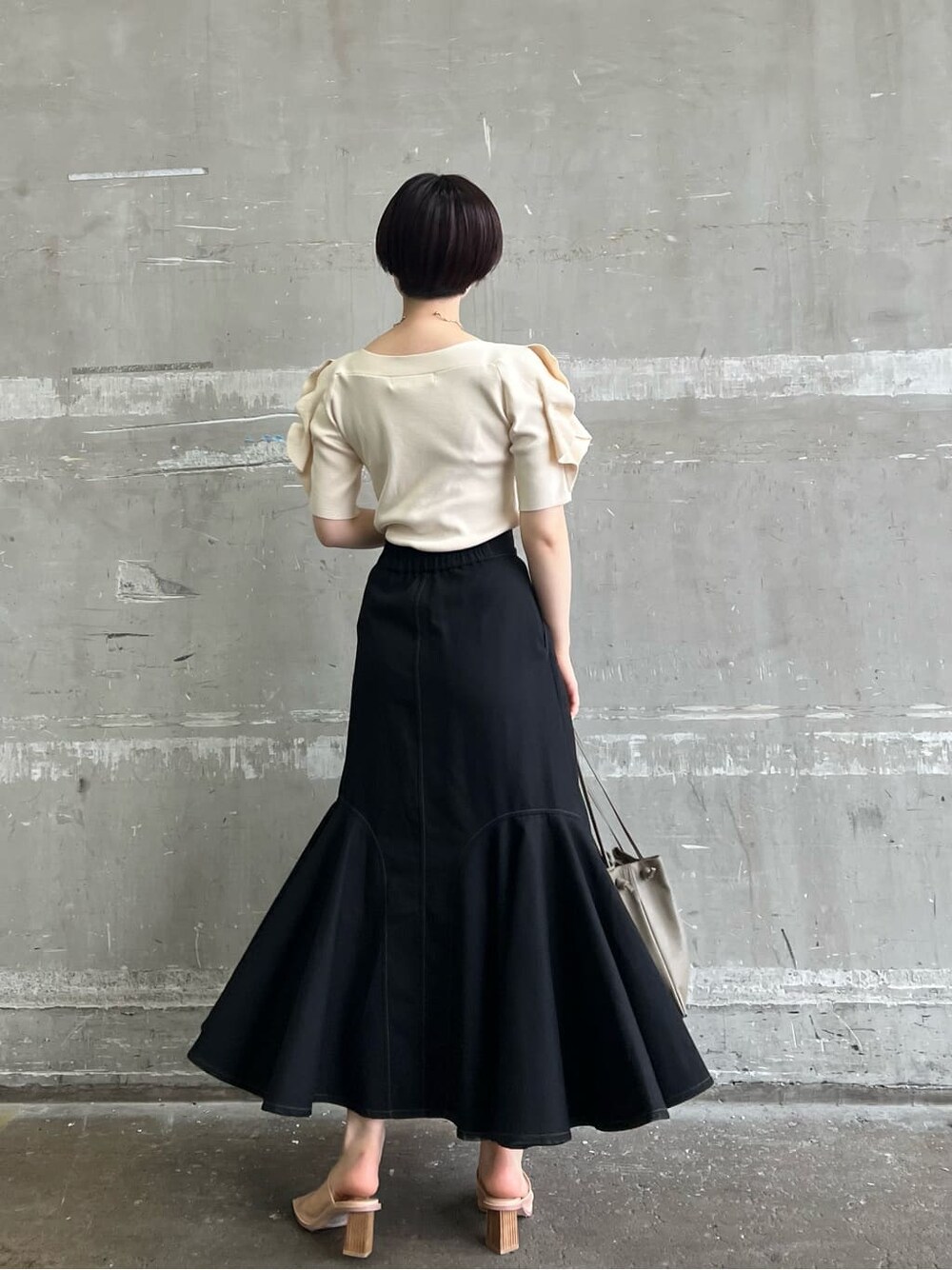 ベージュ系のハンドバッグ、ブラック系のスカート、ホワイト系のニット/セーターを着用したレディースの夏コーディネートの4枚目の写真