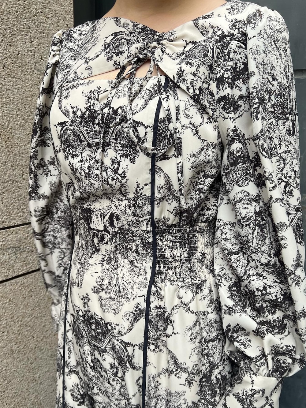 ホワイト系のノーカラーコート、ホワイト系のワンピース、ベージュ系のブーツを着用したレディースの冬コーディネートの5枚目の写真